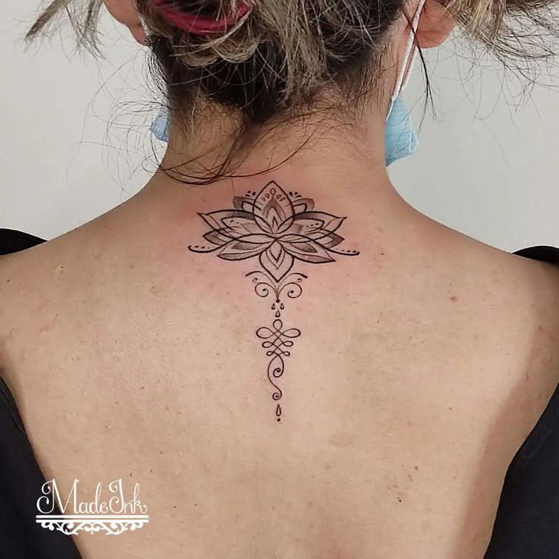 Fine line lotus unalome tattoo on the upper back.