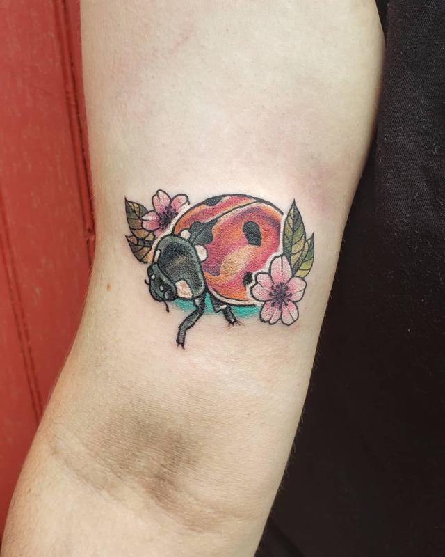 Small pink rose and ladybug tattoo on the inner